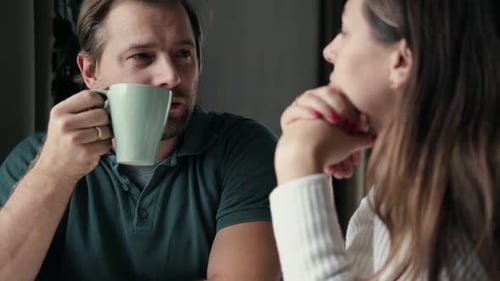 Man and Woman Talking Indoors Over Coffee