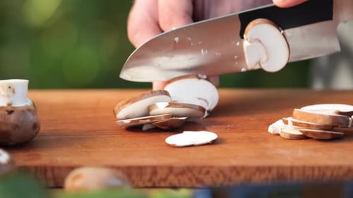 a young man cuts brown mushrooms on a wooden board close up