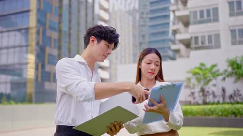 Asian young businessman and woman partner working outdoors in the city.