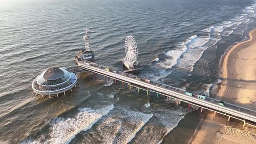 The Hague, Netherlands. A pier with amusement rides. An aerial view of the wide beach and waves.