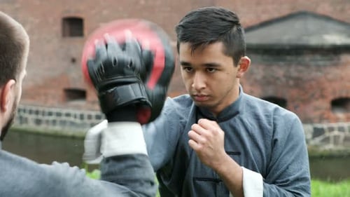 Men Practicing Martial Arts Outdoors Near Brick Building