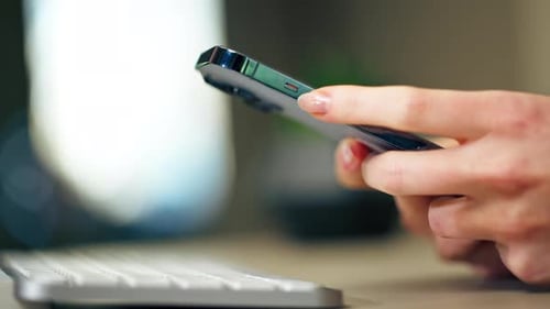Very Closeup of Large New Blue Phone with Three Cameras in Which Women Hands Scroll Through the News
