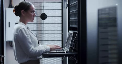 Woman Works on Laptop in Server Room