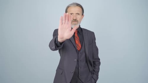 Man in Suit Posing with a Stop Gesture