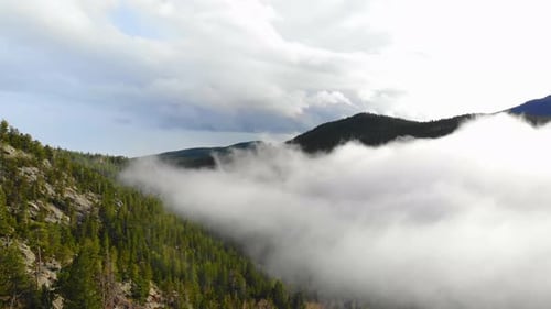 Low Clouds And Fog Over Colorful Rocky Mountain Alpine Valley Hillside. 4K Drone.