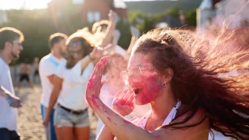 Joyful Woman Splashes Colored Powder on Cheeks Puts Out Tongue Has Fun at Holi Festival in Slow