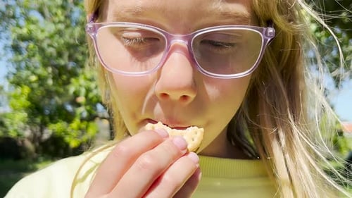 Child Eating Cookie Outdoors in the Daytime