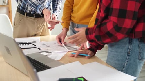 Team Collaborates on Documents and Laptops at Workplace
