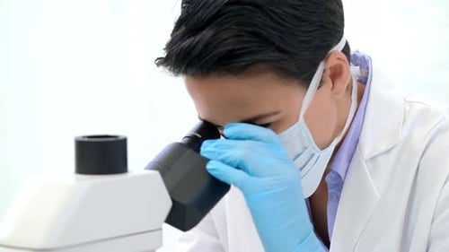 Medical Professional Looking Through Microscope in Lab