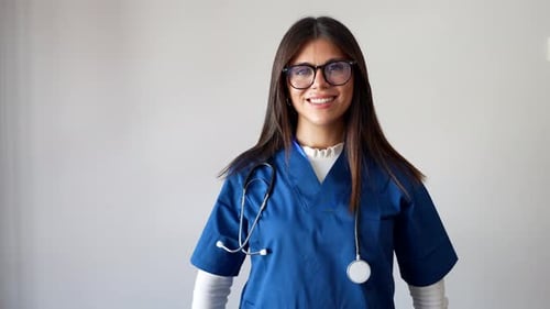 Smiling young healthcare worker in blue scrubs indoors