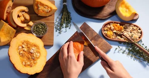 Woman cutting pumpkin on light blue background, above view