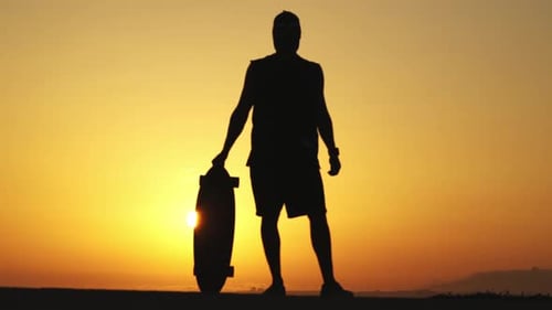 Skateboarder Silhouette with Skateboard at Sunrise