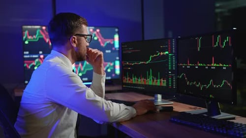 Focused Man Analyzes Financial Data in Blue-Lit Office