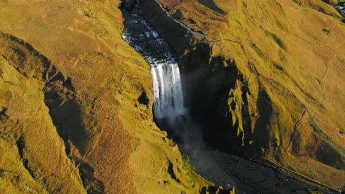 Skogafoss Waterfall, Iceland. Aerial Drone View Of Large Icelandic Waterfall Surrounded By Yellow Mo