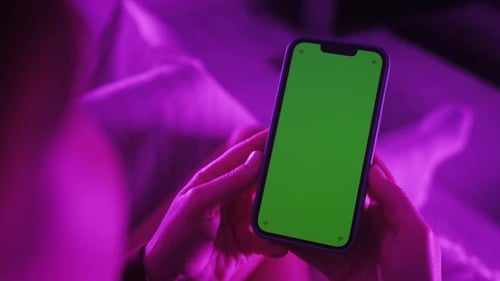 Back View of Woman Holding Chroma Key Green Screen Smartphone Watching Content Without Touching or