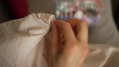 Les mains d'une couturière qualifiée effectuent des points froncés délicats sur des outils de couture en tissu blanc avec douceur