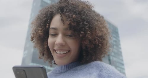 Smiling Woman Using Mobile Phone in City