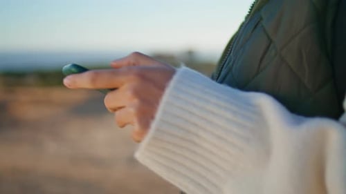 Unrecognized tourist woman messaging on phone during mountain hiking adventure trip