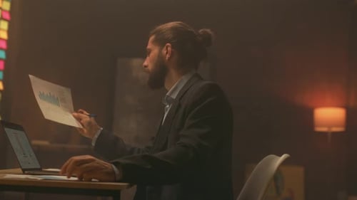 Man Analyzes Data Charts at Desk Late at Night