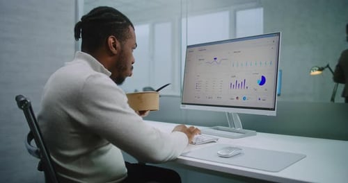 Man Eating Lunch at Computer in Modern Office
