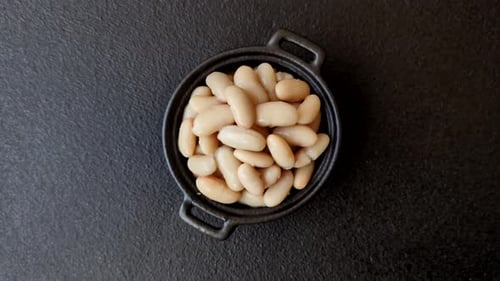 Overhead shot of white beans in a black bowl