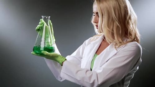 Female Scientist Examine Flask With Green Liquid Attractive Woman Researcher Making Experiment In
