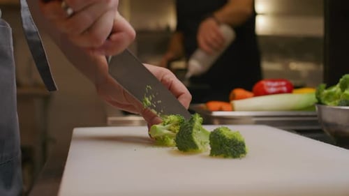 Chef Hands Slicing Fresh Broccoli on Cutting Board in Restaurant Kitchen