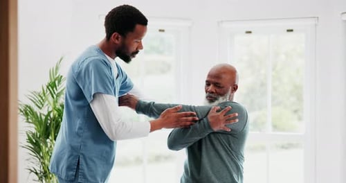 Physical Therapist Assists Senior Man with Arm Stretching