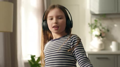 Happy Girl Dancing and Singing with Headphones at Home