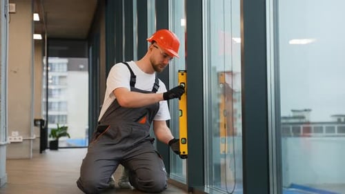 Construction Worker Using Spirit Level to Install Window