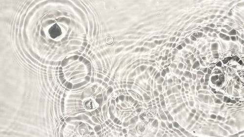 Top View Slow Motion of Drop Falls Into Water and Diverging Circles of Water Sun and Shadows Water