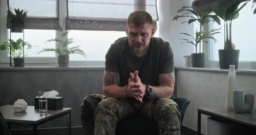 Worried Man Sits in Chair Indoors