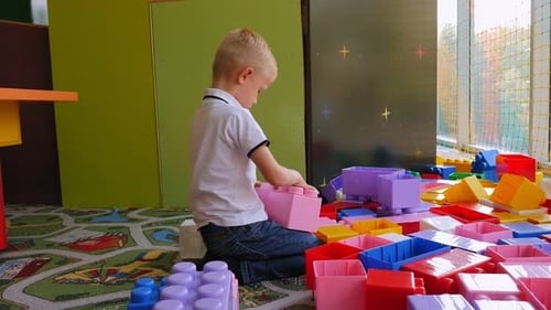 Fair-Haired Child Playing with Colorful Blocks on Carpet