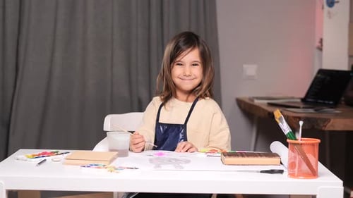 Portrait of a Little Girl Drawing with Paints and a Paintbrush