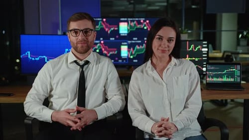 Portrait of Two Traders Brokers in Dark Office In the Background Monitors Show Various Stock Market