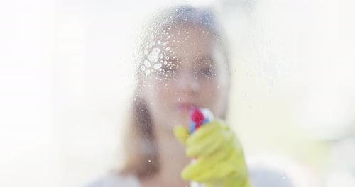 4k video footage of a young woman cleaning the windows with a squeegee at home