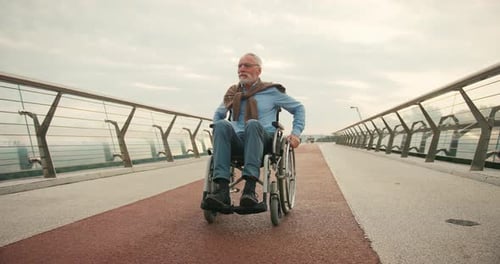 Focused Man Propels Wheelchair Forward on Bridge Walkway