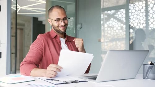 Young Adult Man Celebrates Work Success in Office