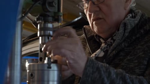 Senior caucasian worker putting drill bit in a drilling in a workshop
