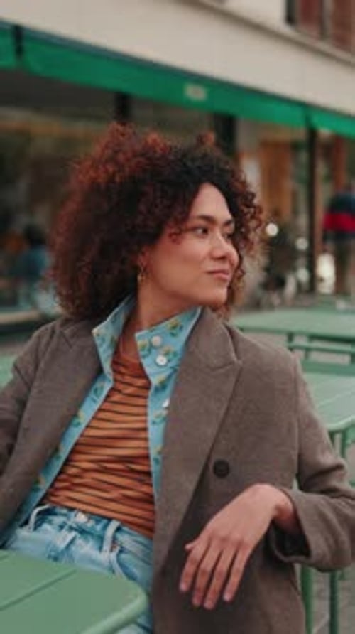 Vertical video,Thoughtful Woman Sits at Outdoor Cafe