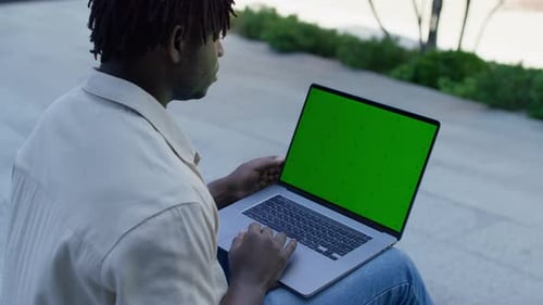 Man Using Laptop with Green Screen Outdoors