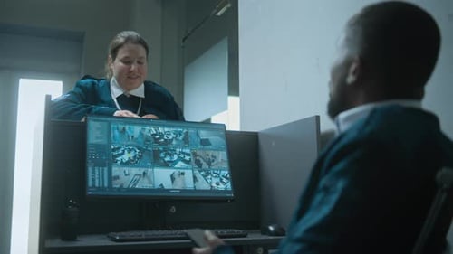 Two Security Guards Monitor CCTV Footage on Computer