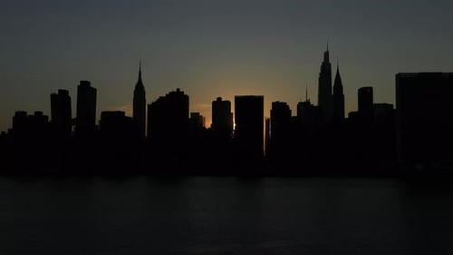 slow trucking shot of a silhouetted Manhattan skyline at sunset, just after the rare