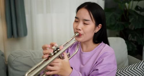 Woman Plays Trumpet Indoors on Couch