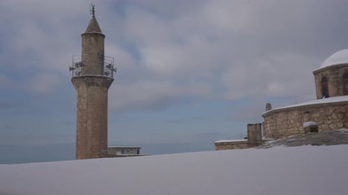 Während die Kamera nach rechts schwenkt, sehen wir das schneebedeckte Dach und die Kuppel von Emir Hamam, einem von Mardin'