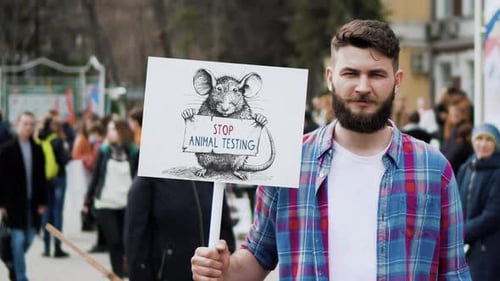 Un homme tient une bannière avec un rat de laboratoire contre les tests sur les animaux pour protester contre l'exploitation