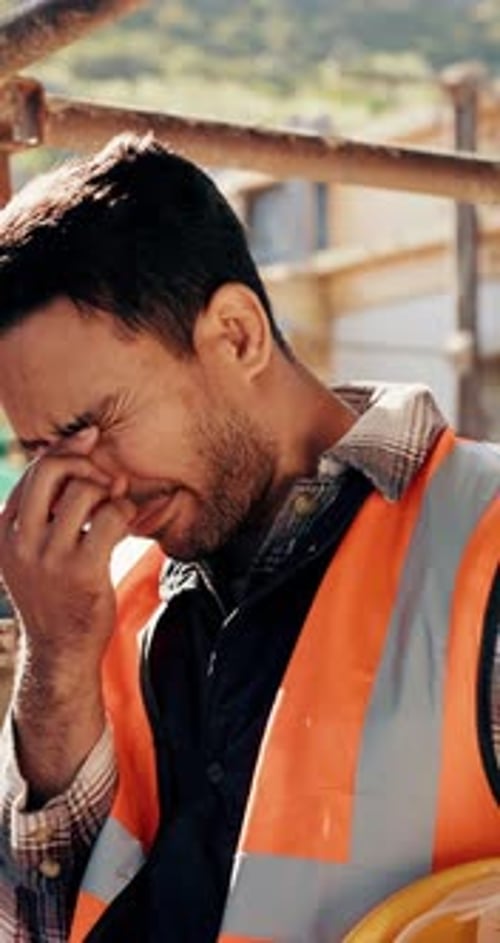 Construction, worker and headache with helmet outdoor, overwhelmed or overworked at building site