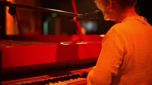 Woman Plays Red Piano Under Warm Stage Lights
