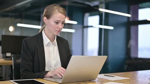 Ehrgeizige junge Geschäftsfrau arbeitet im Büro am Laptop
