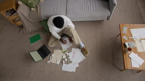 Concerned Man Managing Household Bills and Expenses on Living Room Floor